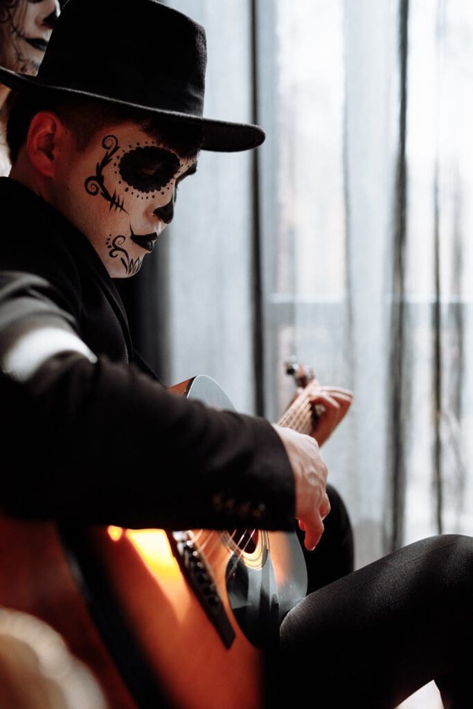 Man in Halloween costume plays a Halloween song with his guitar